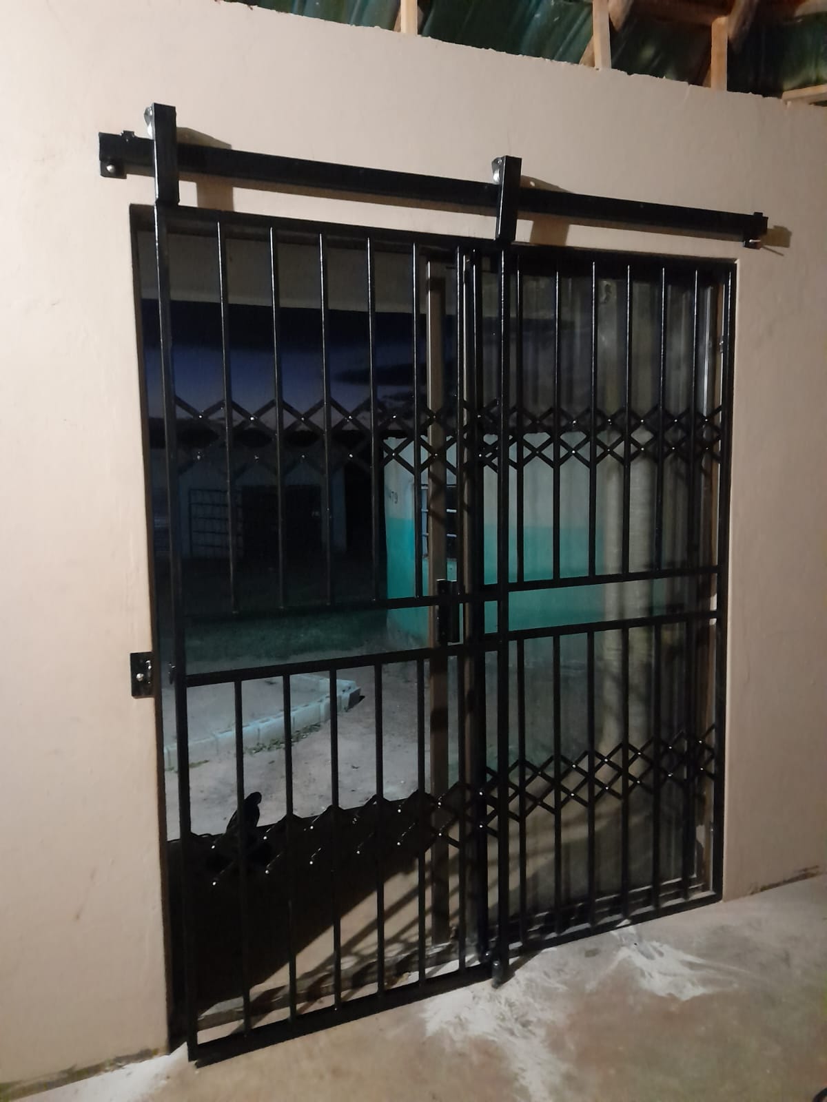 Black trellis sliding security door at night